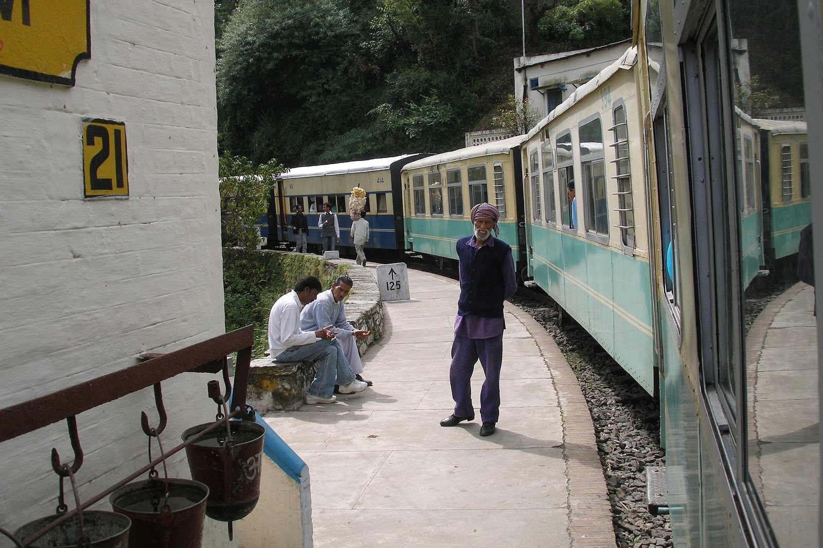 The narrow-gauge Kalka-Shimla toy train waiting at a small hillside station platform with cream and teal carriages